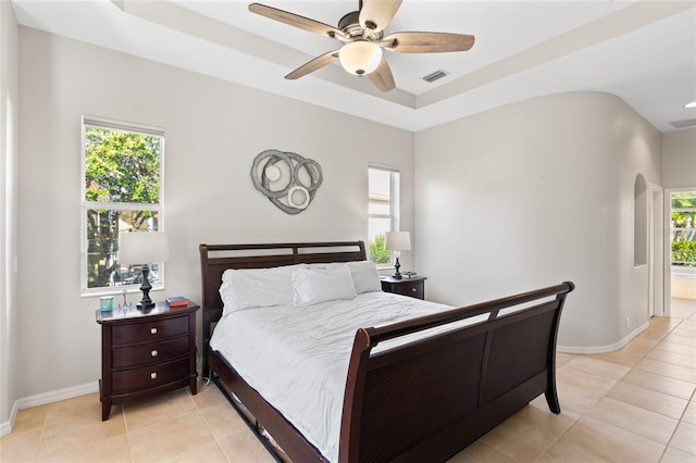 bedroom with baseboards, multiple windows, visible vents, and a raised ceiling