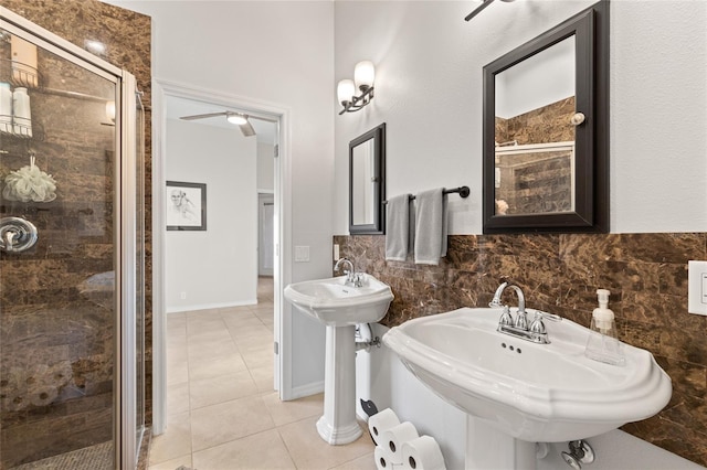 full bath with two sinks, a shower stall, tile walls, and tile patterned floors