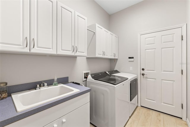 laundry area with light wood finished floors, washing machine and clothes dryer, a sink, and cabinet space