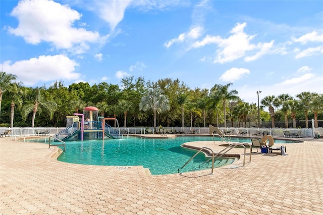 pool featuring a water play area, fence, and a patio