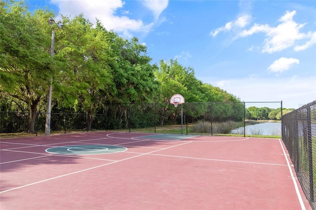 view of sport court featuring community basketball court, a water view, and fence