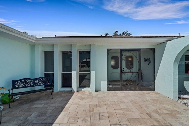 view of exterior entry with a patio area and stucco siding