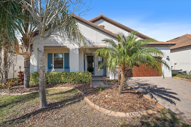 view of front of property featuring an attached garage, a porch, decorative driveway, and stucco siding