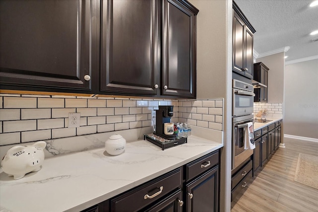 kitchen featuring light stone counters, crown molding, black electric stovetop, light wood finished floors, and backsplash