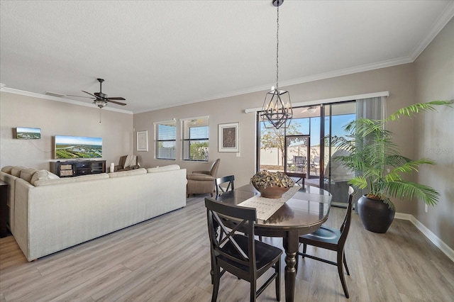 dining space with baseboards, crown molding, light wood finished floors, and ceiling fan with notable chandelier