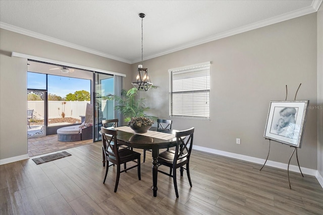 dining space featuring baseboards, ornamental molding, a chandelier, and wood finished floors