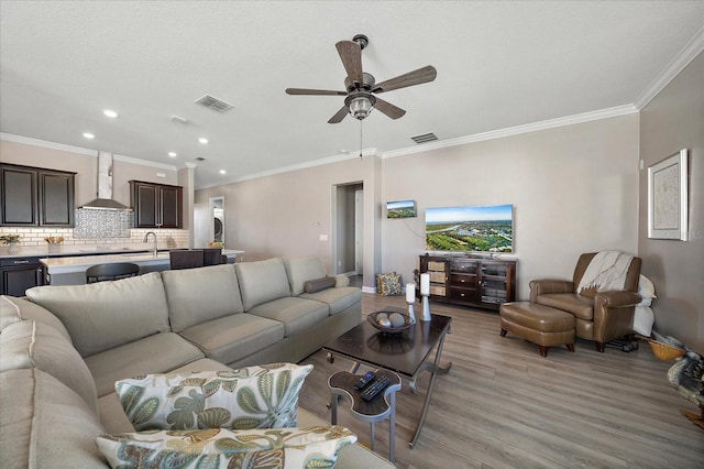 living room featuring visible vents, crown molding, and light wood-style flooring