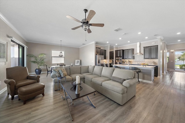 living area with light wood finished floors, baseboards, visible vents, and ceiling fan with notable chandelier