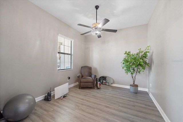 living area featuring a ceiling fan, light wood-style flooring, and baseboards