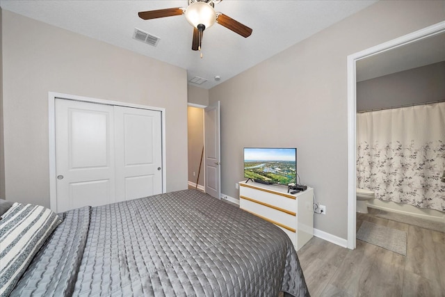 bedroom featuring ensuite bathroom, wood finished floors, visible vents, baseboards, and a closet