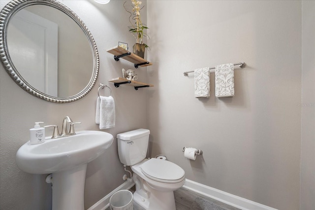 bathroom featuring baseboards, a sink, toilet, and wood finished floors