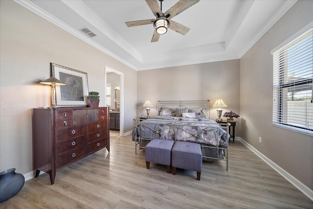 bedroom featuring a tray ceiling, visible vents, ensuite bathroom, light wood-style floors, and baseboards