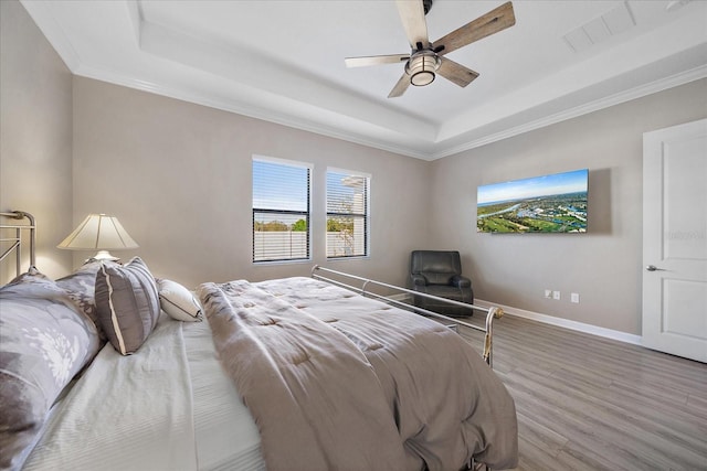 bedroom with baseboards, visible vents, a raised ceiling, ceiling fan, and wood finished floors