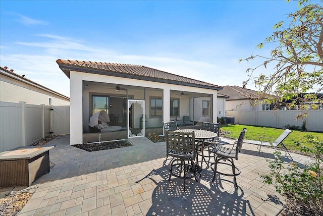 view of patio featuring a sunroom, a fenced backyard, a ceiling fan, and outdoor dining space