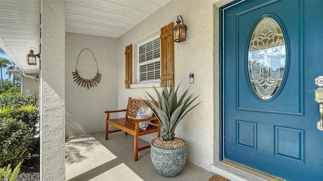 view of exterior entry featuring stucco siding and covered porch