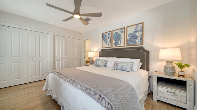 bedroom with visible vents, multiple closets, wood finished floors, and a ceiling fan