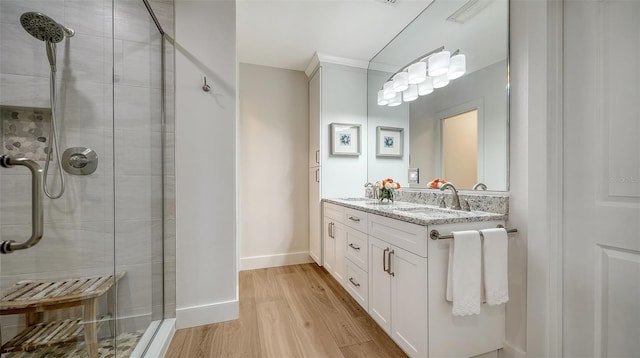 full bath featuring double vanity, a sink, a stall shower, and wood finished floors