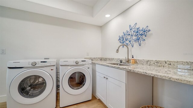 clothes washing area featuring washer and clothes dryer, recessed lighting, light wood-style flooring, cabinet space, and a sink