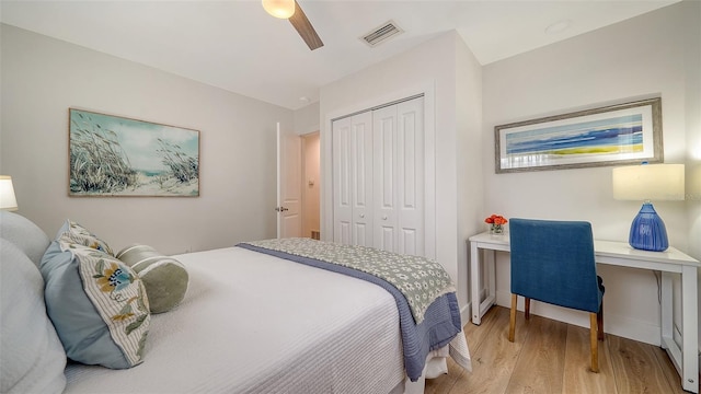 bedroom with a ceiling fan, wood finished floors, visible vents, and a closet