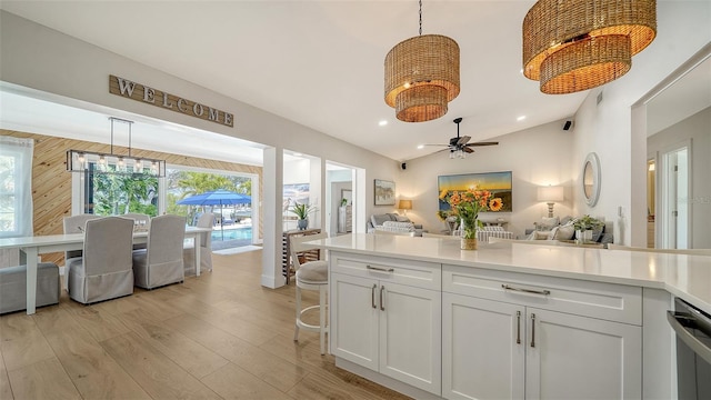 kitchen with light wood finished floors, light countertops, white cabinetry, decorative light fixtures, and open floor plan