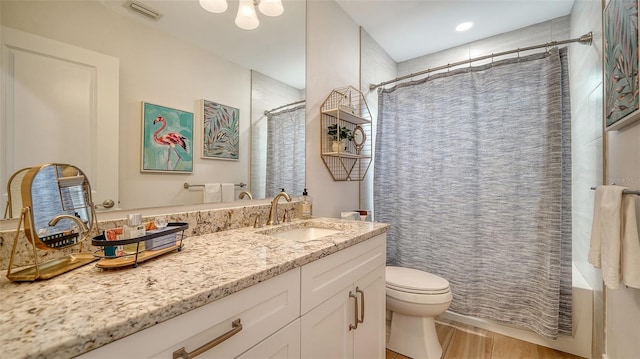 full bathroom with vanity, shower / tub combo with curtain, toilet, visible vents, and wood finished floors