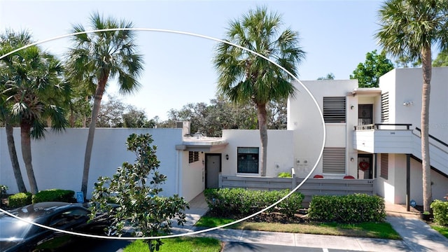 view of front of home featuring a fenced front yard, uncovered parking, stairway, and stucco siding