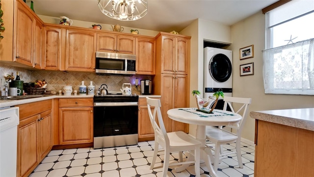 kitchen with stacked washer and dryer, stainless steel appliances, light floors, and light countertops