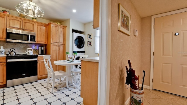 kitchen with stainless steel appliances, light countertops, light floors, tasteful backsplash, and stacked washer and clothes dryer