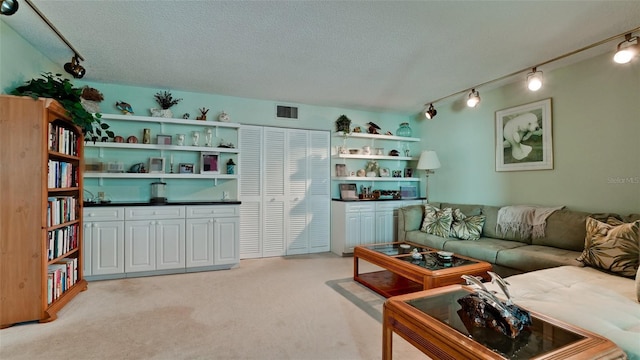 living area featuring light carpet, track lighting, visible vents, and a textured ceiling