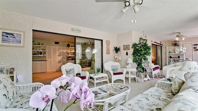 living room with a textured ceiling, a textured wall, ceiling fan, and carpet