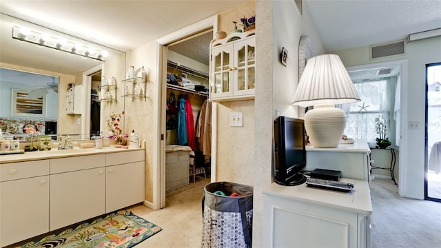 bathroom with a walk in closet, vanity, visible vents, and a ceiling fan