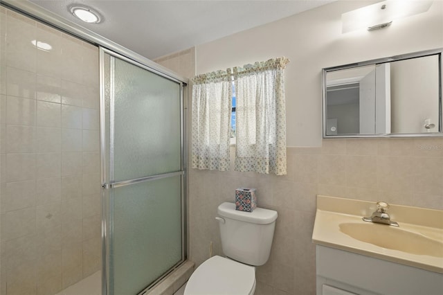 bathroom with a stall shower, vanity, toilet, and tile walls