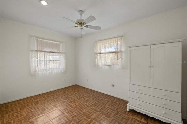 unfurnished bedroom with multiple windows, a ceiling fan, and baseboards