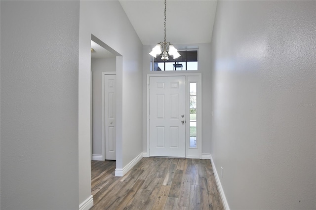 foyer entrance featuring a healthy amount of sunlight, a notable chandelier, baseboards, and wood finished floors