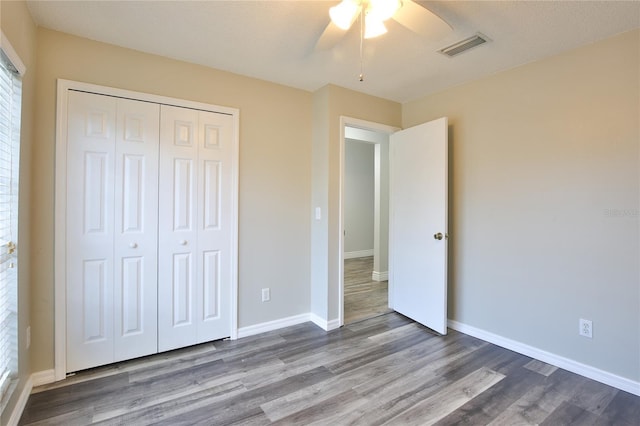 unfurnished bedroom with baseboards, visible vents, a ceiling fan, wood finished floors, and a closet