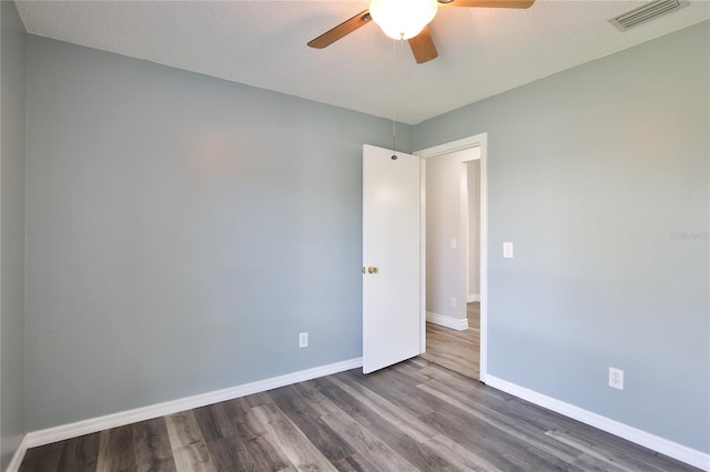 unfurnished room with dark wood-type flooring, visible vents, ceiling fan, and baseboards