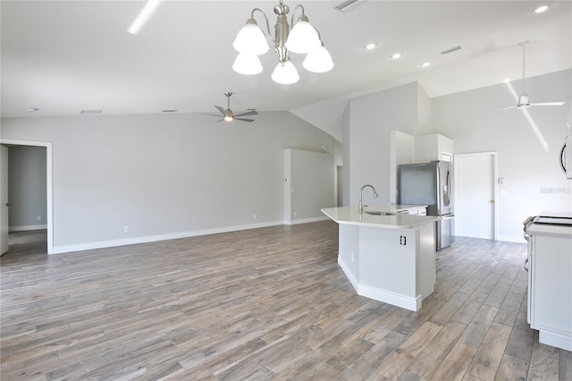 kitchen with light wood finished floors, light countertops, freestanding refrigerator, white cabinets, and ceiling fan with notable chandelier