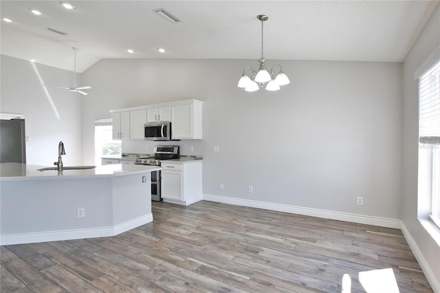 kitchen with stainless steel appliances, wood finished floors, a sink, visible vents, and white cabinetry