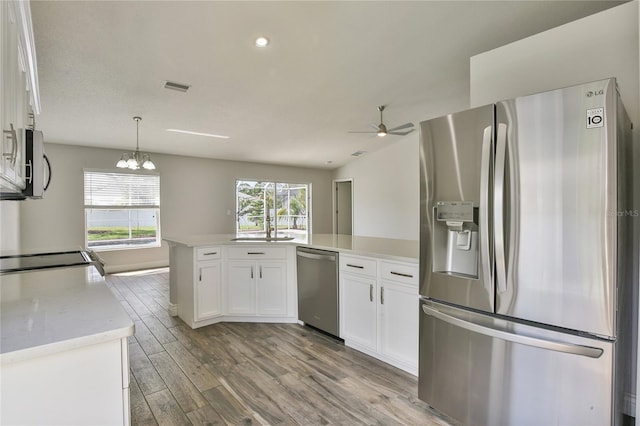 kitchen featuring stainless steel appliances, wood finished floors, visible vents, white cabinetry, and light countertops