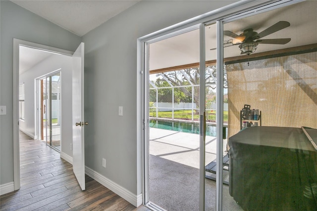 doorway featuring lofted ceiling, ceiling fan, baseboards, and wood finished floors