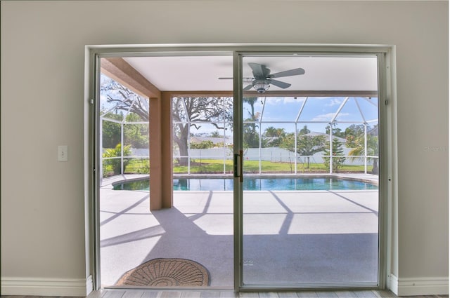 doorway featuring a sunroom, ceiling fan, and baseboards