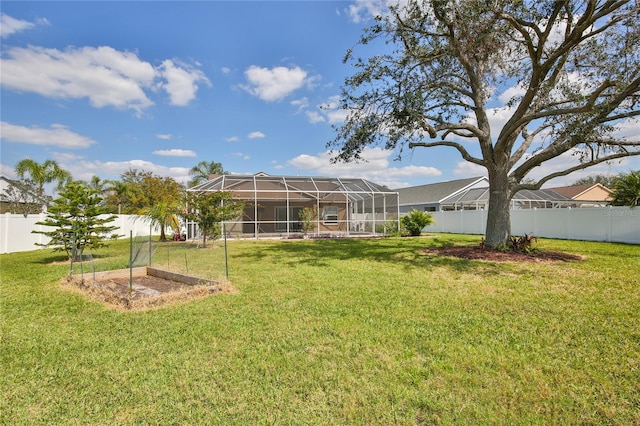 view of yard featuring a fenced backyard, a vegetable garden, and a lanai