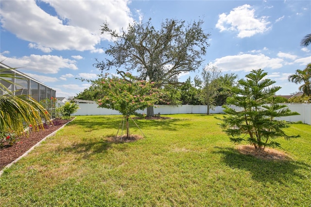 view of yard featuring glass enclosure and a fenced backyard