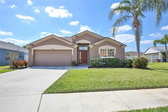 single story home with stucco siding, concrete driveway, a front yard, fence, and a garage