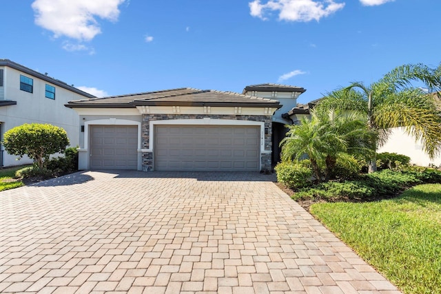 view of front facade featuring decorative driveway, stucco siding, a garage, stone siding, and a tiled roof