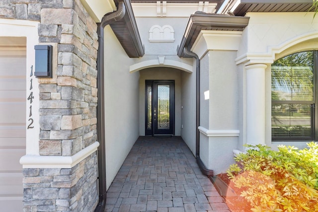 view of exterior entry featuring stone siding and stucco siding