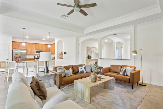 living area featuring baseboards, visible vents, a tray ceiling, and crown molding