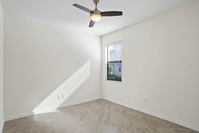 empty room with ceiling fan, light tile patterned floors, and baseboards