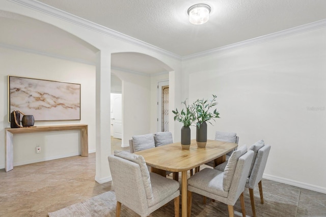 dining space featuring ornamental molding, arched walkways, a textured ceiling, and baseboards