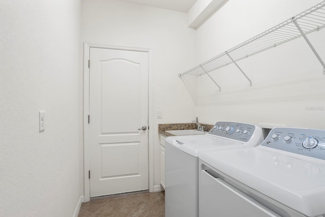 washroom with light tile patterned flooring, a sink, baseboards, independent washer and dryer, and cabinet space